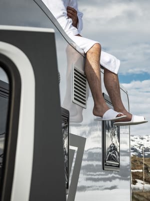 man relaxing on top of his Brinkley RV in the mountains living a luxury rv lifestyle